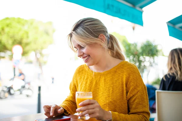 Портрет Улыбающейся Молодой Женщины Сидящей Возле Кафе Напитком Смотрящей Мобильный — стоковое фото