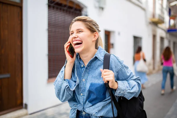 明るい若い女性がバッグを持って歩き 街の外の携帯電話で話す姿 — ストック写真
