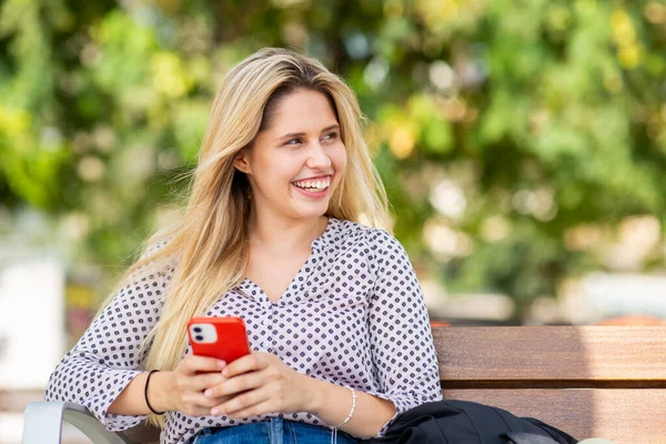 魅力的な若い女性の肖像画ベンチに座って外で携帯電話 — ストック写真