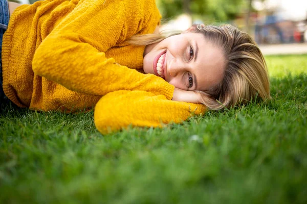 Çimenlerin Üzerinde Uzanmış Kameraya Bakıp Gülümseyen Güzel Bir Genç Kadının — Stok fotoğraf