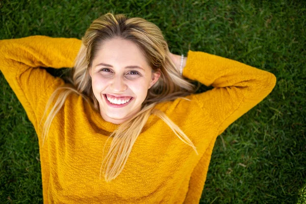 一个微笑的年轻女子躺在草地上 双手放在脑后的画像 — 图库照片