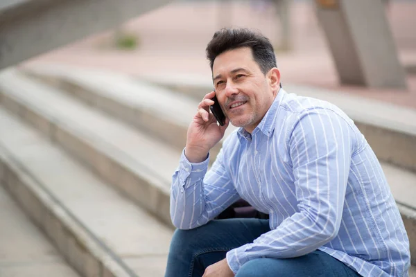 Портрет Уверенного Пожилого Латинского Мужчины Сидящего Улице Ступеньках Разговаривающего Мобильному — стоковое фото