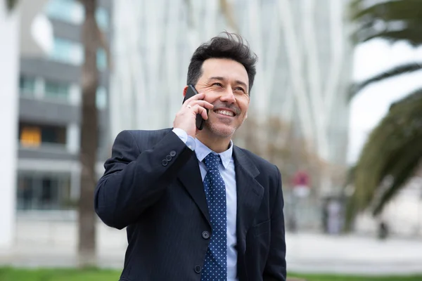 幸せな成熟したビジネスマンの携帯電話で話をし 市内の外を歩く笑顔の肖像 — ストック写真