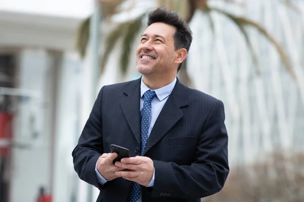 外を歩いて笑っている携帯電話を持つビジネスマンの肖像 — ストック写真
