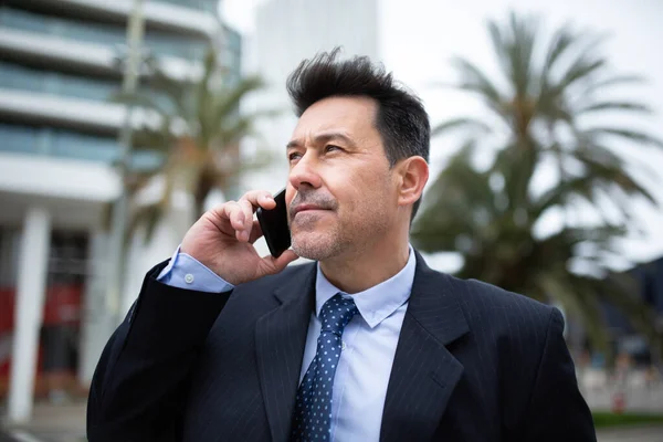 都市の外に立って 携帯電話で話す成熟したビジネスマンのクローズアップ肖像画 — ストック写真