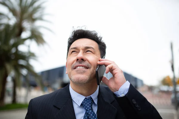 外に立って携帯電話で話している古いビジネスマンのクローズアップ肖像画 — ストック写真