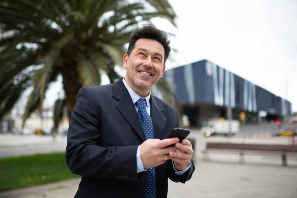 一个快乐的商人的画像 他带着手机走在外面 望着外面笑着 — 图库照片