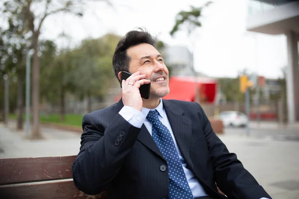 Portrét Šťastného Zralého Obchodníka Sedícího Lavičce Mluvícího Mobilním Telefonu — Stock fotografie