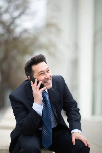 Портрет Счастливого Взрослого Бизнесмена Сидящего Снаружи Разговаривающего Мобильному Телефону — стоковое фото