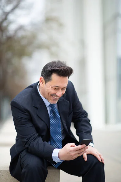 幸せな成熟したビジネスマンの肖像携帯電話上のテキスト外に座って — ストック写真