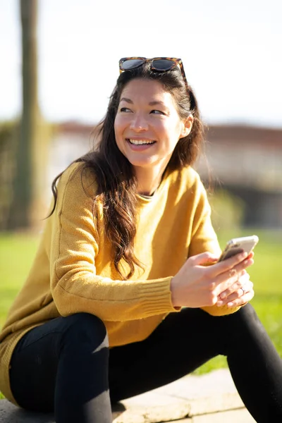 Retrato Una Mujer Sonriente Sentada Afuera Sosteniendo Teléfono Móvil Mirando —  Fotos de Stock