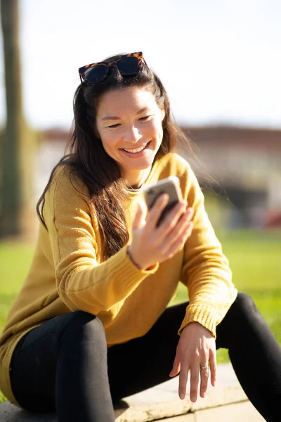 Портрет Улыбающейся Молодой Китайской Женщины Сидящей Снаружи Помощью Мобильного Телефона — стоковое фото