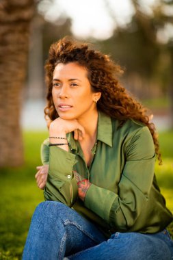 Güzel, genç bir Latin kadının portresi. Dışarıda oturuyor, başka tarafa bakıyor ve eli çenesinde düşünüyor.