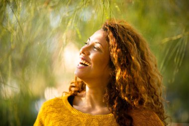 Güzel bir genç kadının yakın portresi. Bir yaz günü başka bir yere bakıyor ve dışarıda gülümsüyor.