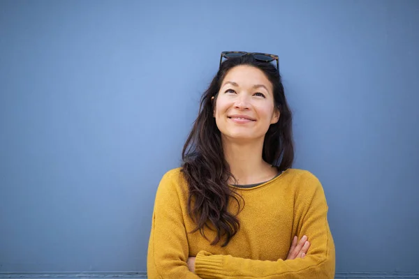 Kollarını Kavuşturup Mavi Duvara Bakıp Gülümseyen Asyalı Güzel Bir Kadının — Stok fotoğraf