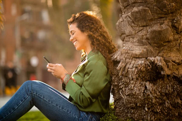 Zijportret Van Lachende Jonge Vrouw Met Behulp Van Mobiele Telefoon — Stockfoto