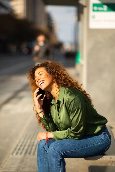 携帯電話で話している美しい若い女性の肖像画と笑いながら街の通りに座って — ストック写真