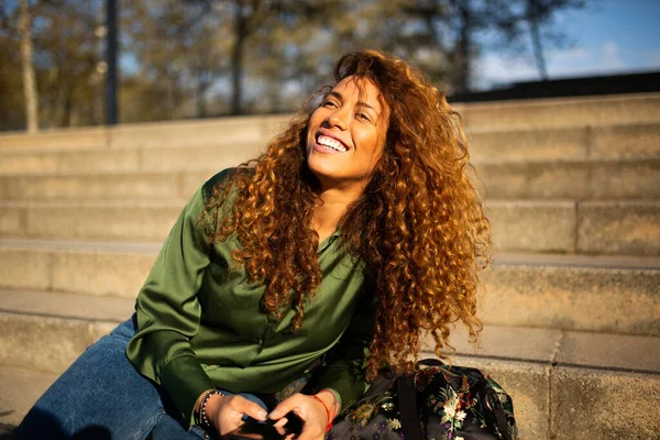 Портрет Молодої Іспаномовної Жінки Сидить Сходах Мобільним Телефоном Дивлячись Посміхаючись — стокове фото