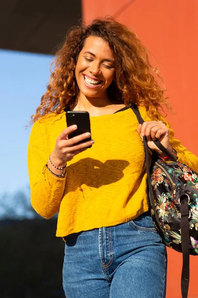 若い混合人種の女性の肖像携帯電話やバッグで外を歩く — ストック写真