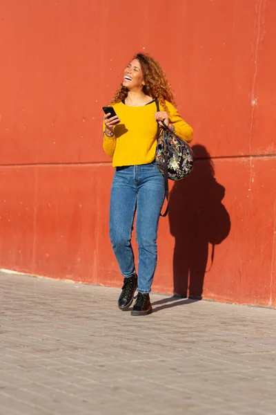 満面の笑みを浮かべて若い女性の肖像画袋と携帯電話で壁で外 — ストック写真