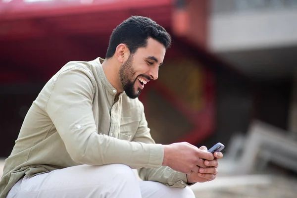 外面用手机笑着的英俊阿拉伯年轻人的侧面肖像 — 图库照片