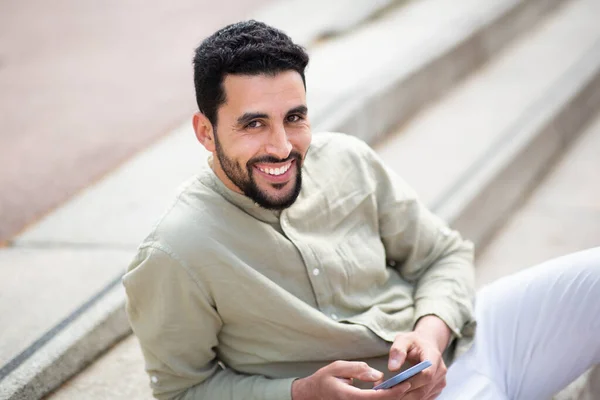 Portrét Pohledného Mladého Muže Středního Východu Sedícího Venku Schodech Mobilním — Stock fotografie