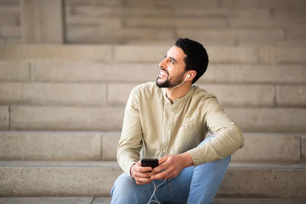 Retrato Homem Árabe Sorridente Ouvindo Música Com Telefone Celular Sentado — Fotografia de Stock