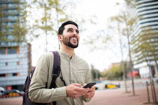 バッグと携帯電話で街の外を歩く幸せな若者の肖像画 — ストック写真
