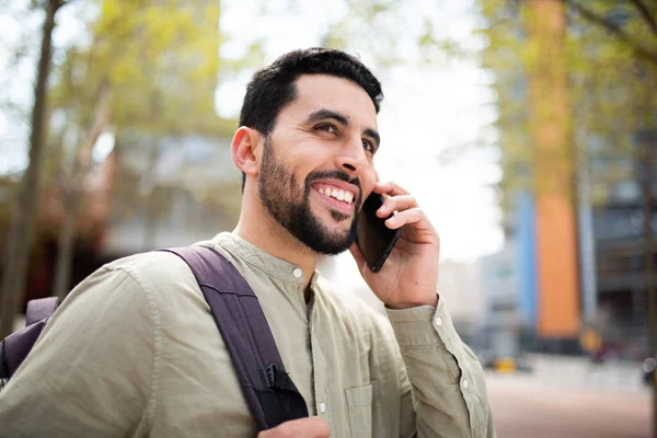 ハンサムな若い中東人の肖像画袋で外を歩くと携帯電話で話す — ストック写真