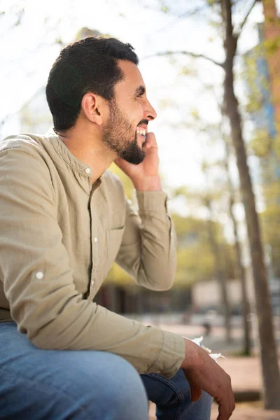 Sidoporträtt Leende Ung Arabisk Kille Pratar Mobiltelefon Sitter Utanför — Stockfoto