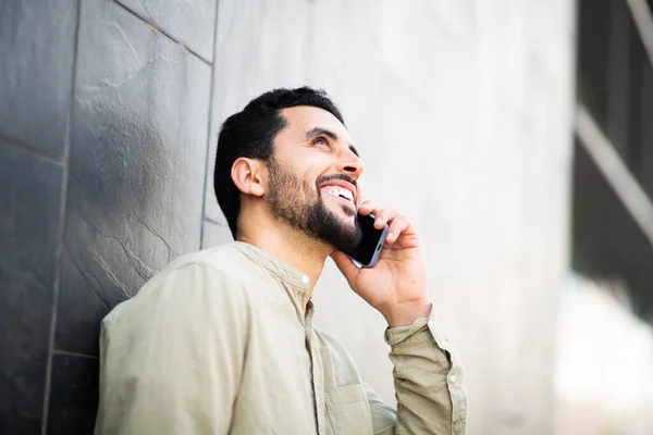Портрет Улыбающегося Молодого Араба Разговаривающего Мобильному Телефону Прислонившегося Стене — стоковое фото