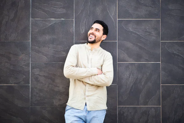 一个自信的北非年轻人的画像 手挽手站在黑色的瓷砖墙上 面带微笑地望着别处 — 图库照片