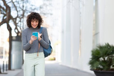 Şehirde çantalı ve telefonlu güzel bir genç kadının portresi.