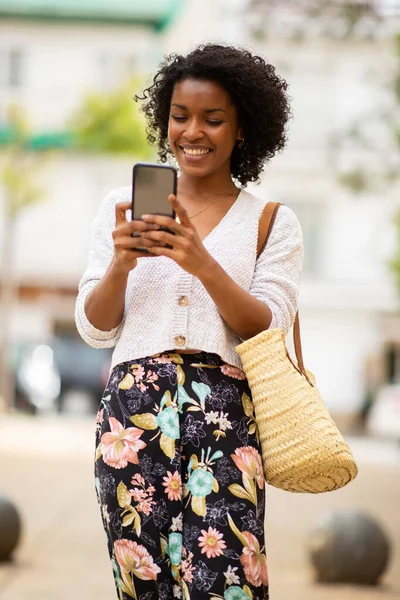 ポートレート笑顔アフリカ系アメリカ人女性が携帯電話で街を歩く — ストック写真