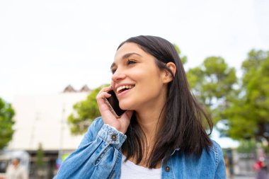 Cep telefonuyla konuşan gülümseyen genç bir kadın.