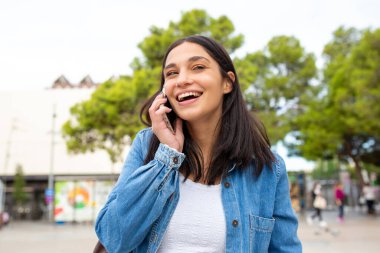 Cep telefonuyla konuşan gülümseyen genç bir kadın portresi