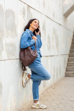 Tam vücut portresi. Cep telefonu kullanan genç bir kadın.