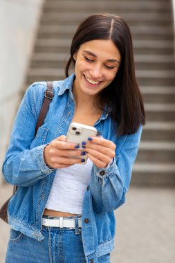 Cep telefonu kullanan gülümseyen bir kadın.