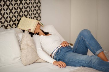 Yatakta kitap kaplamalı genç bir kadın portresi.