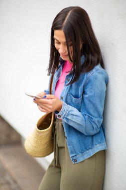 Cep telefonu kullanan çantalı genç bir kadın portresi