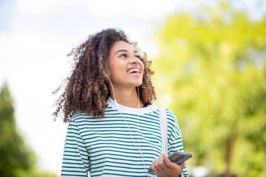 Güzel bir portre cep telefonu ve kulaklıkları olan Afro-Amerikan bir kadın.