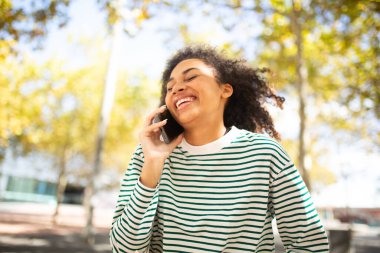 Cep telefonuyla konuşan gülen genç bir kadın portresi