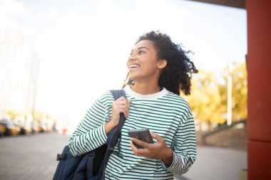Portre öğrencisi kampüste cep telefonu ve çantasıyla dolaşıyor.
