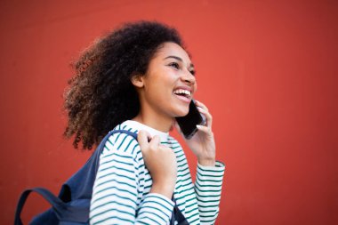 Yanında çantalı genç bir kadın cep telefonuyla konuşuyor.