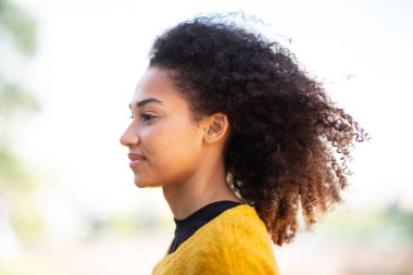 Yan portresi güzel, kıvırcık saçlı Afrikalı Amerikalı bir kadın.