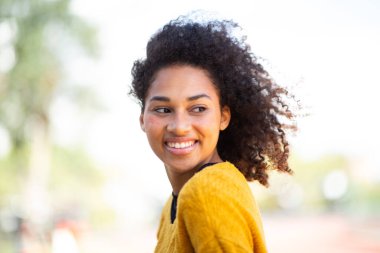 Omuzlarının üzerinden bakan kıvırcık saçlı genç bir kadın.