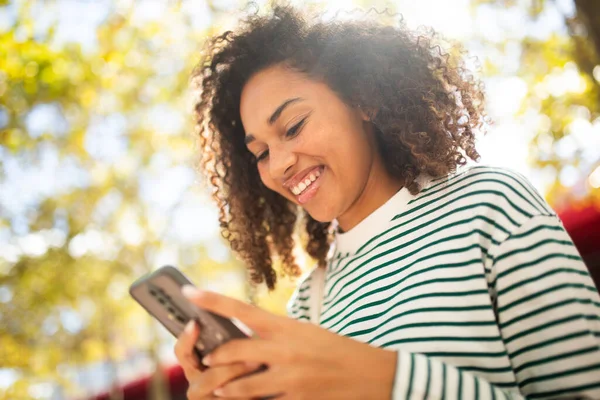 stock image Close up portrait smiling young african american woman looking at mobile phone