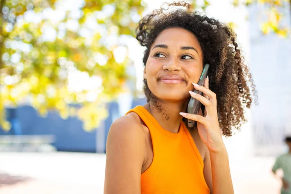 Cep telefonuyla konuşan gülümseyen genç bir kadın portresi