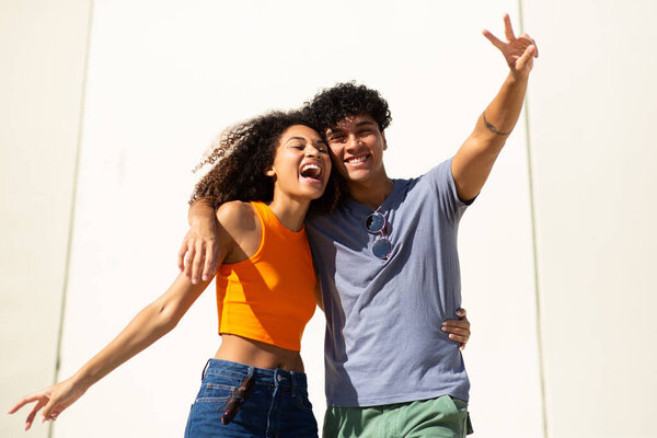 Portrait of cheerful young couple by white wall