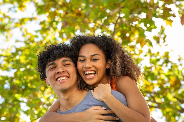 Portrait of happy young couple piggyback ride outdoors